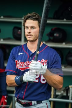 a baseball player holding a bat in the dugout during a game against sports team