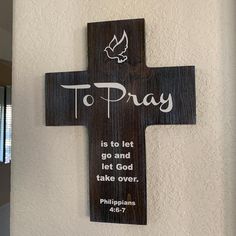 a wooden cross that says to pray is to let go and let god take over