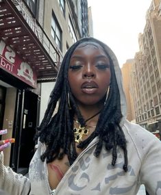 a woman with dreadlocks standing in front of a building holding a toothbrush