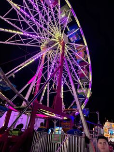 the ferris wheel is brightly lit up at night