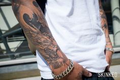 a man with a dragon tattoo on his arm holding onto another person's hand