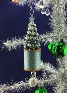 an ornament hanging from a christmas tree decorated with green and silver baubles