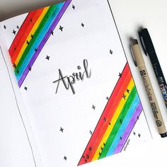 an open notebook with the word april written on it next to two markers and a pen