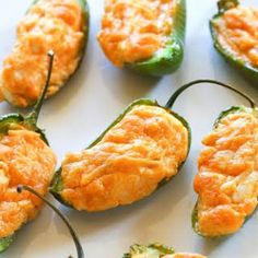 several green peppers with cheese on them sitting on a white plate and ready to be eaten