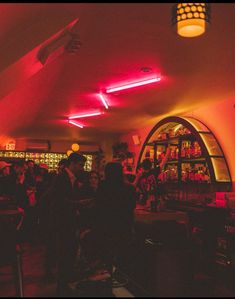 a group of people standing in a room with red lights on the ceiling and shelves