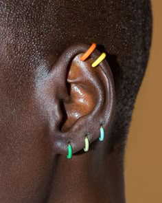 a close up of a person's ear with colored pins in the shape of an ear