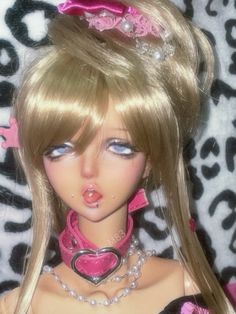 a barbie doll with blonde hair wearing a pink bow and necklace on top of her head