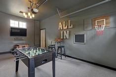 a game room with foosball, basketball hoop and bar stools in it