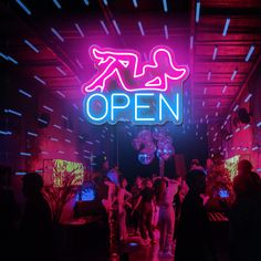 a neon sign that reads open with people dancing in the background at an event or club