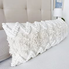 a white pillow sitting on top of a bed next to a beige headboard and pillows