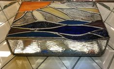 a stained glass box sitting on top of a tiled floor