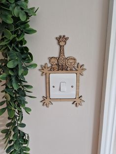 a giraffe and two zebras on a light switch cover in the corner of a room