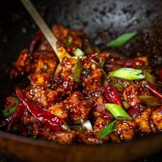 some food is being cooked in a wok with chopsticks on the side