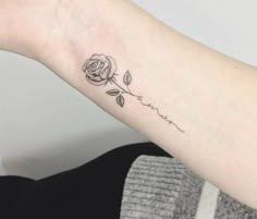 a small rose tattoo on the left inner arm, with words written in cursive writing