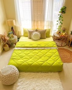 a green bed sitting in the middle of a bedroom next to a window with white curtains