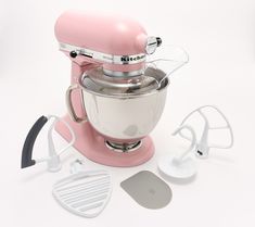 a pink mixer and other kitchen accessories on a white surface