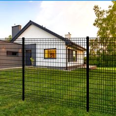 a house behind a fence in the grass