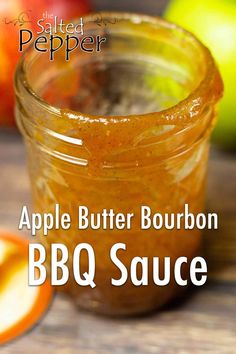 an apple butter bourbon bbq sauce in a glass jar next to sliced apples on a wooden table