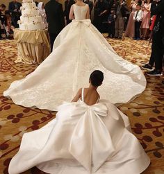 a woman sitting on the floor in front of a wedding dress that is being displayed