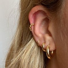 a close up of a person's ear with two gold hoops on it