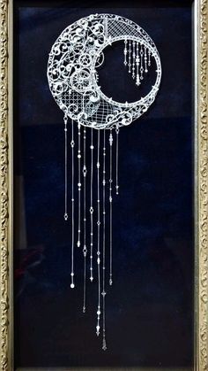 an ornate frame with a drawing of a crescent and beads hanging from it's sides