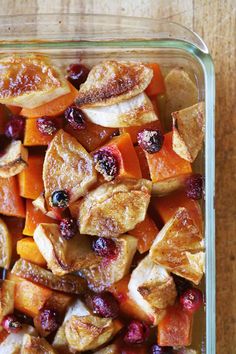 a glass casserole dish filled with cranberry oranges and apples on a wooden table