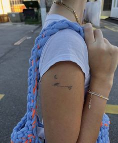 a woman with a tattoo on her left arm holding onto a blue knitted bag