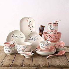 a table topped with dishes and cups covered in pink paintbrushes on top of a wooden table