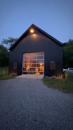 a black barn with its lights on and the front door open at night, lit up