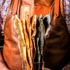 a person holding a brown leather bag filled with different types of bread