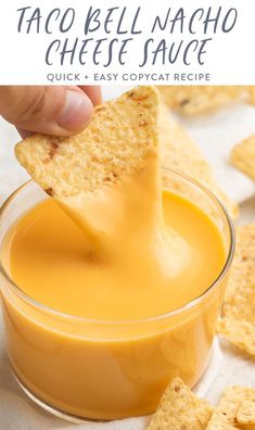 a person dipping cheese into a glass bowl with crackers