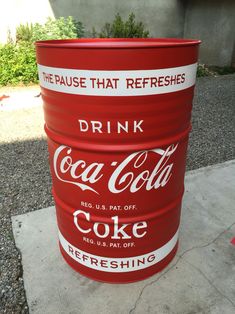 a red metal barrel sitting on top of a sidewalk