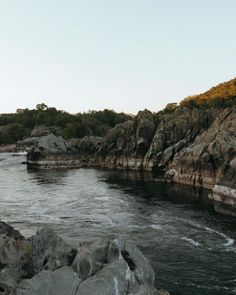 a man standing on top of a rock next to a body of water