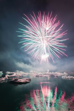 fireworks in the sky over water and icebergs