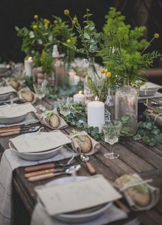 the table is set with place settings and candles for an outdoor dinner party or reception