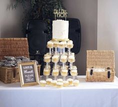 a table topped with lots of cupcakes covered in frosting next to baskets