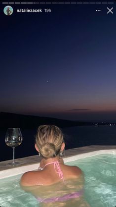 a woman in a hot tub with a glass of wine