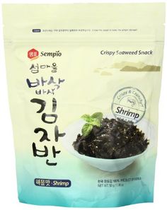 a bag of crispy seaweed snack sitting on top of a white bowl filled with green leaves