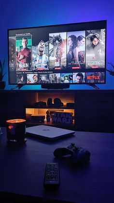 a desk with a remote control and a large screen television in the background at night