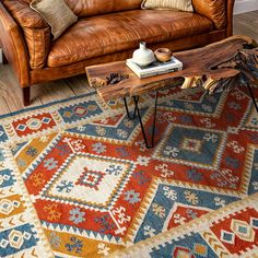 a living room with a leather couch and wooden table on top of the rug in front of it