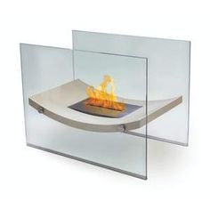 a glass fire pit sitting on top of a white counter next to a wall mounted fireplace