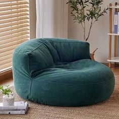 a large green bean bag chair sitting on top of a rug next to a window