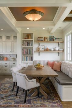 a dining room table with two chairs and a bench in front of bookshelves