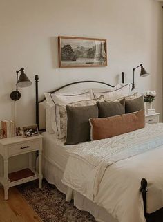 a bed with white sheets and pillows in a bedroom next to a painting on the wall