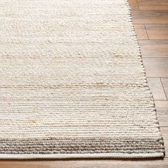 a white and brown rug on top of a wooden floor next to a hard wood floor