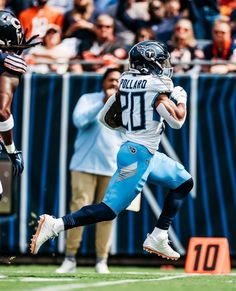 a football player running with the ball in his hand and people watching from the stands