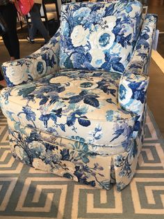 a blue and white flowered chair sitting on top of a rug in a room