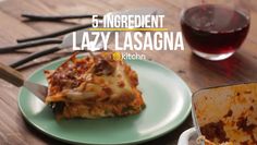 a piece of lasagna on a plate next to a glass of wine