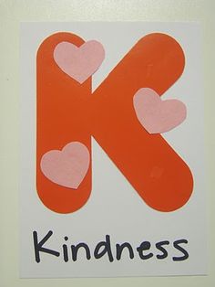 the letter k has hearts on it and is orange with black lettering that says kindness