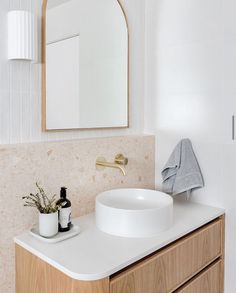 a white sink sitting under a mirror next to a wooden cabinet with a towel on it